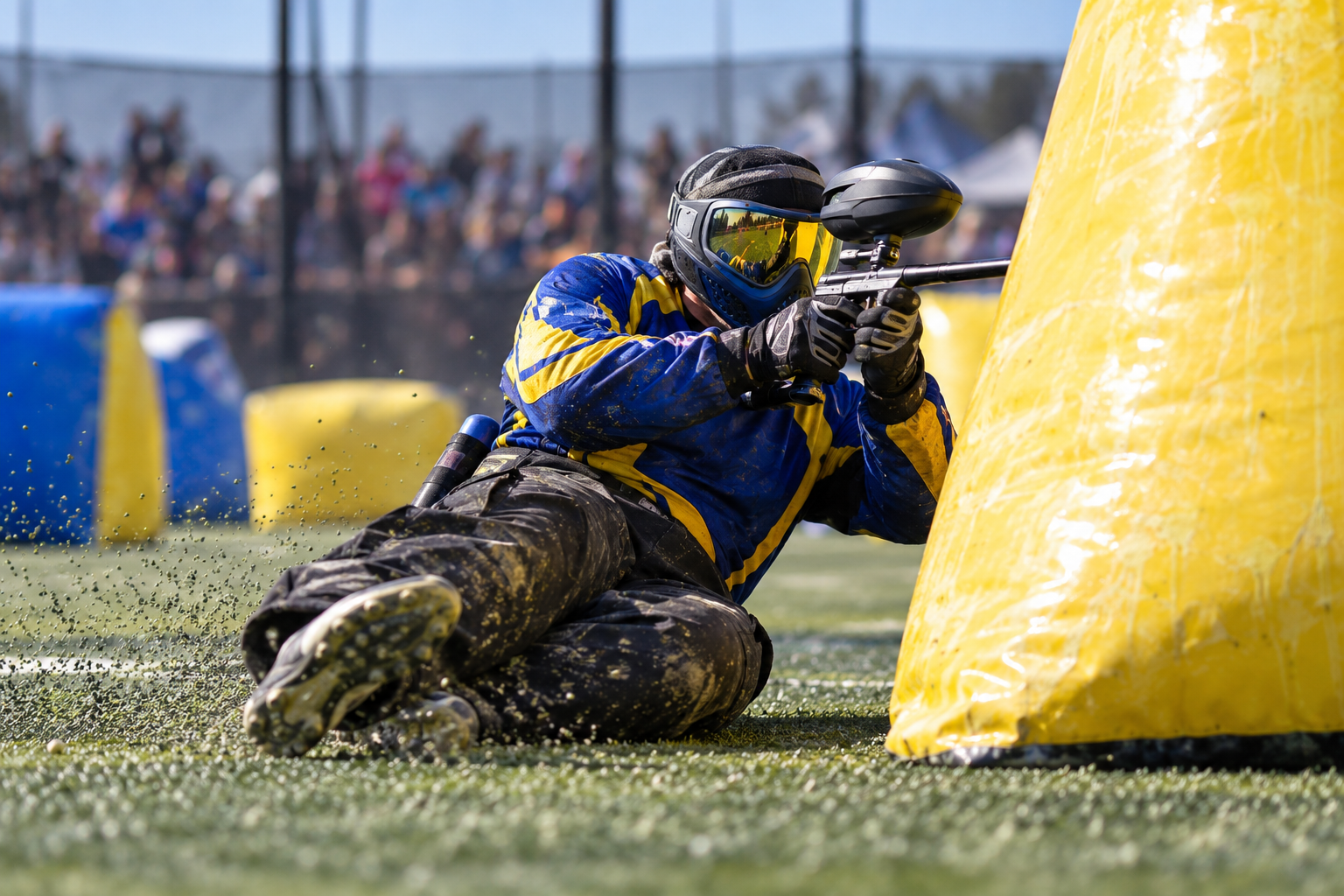 A Berta Boys player sliding into cover behind a yellow inflatable bunker during a tournament game